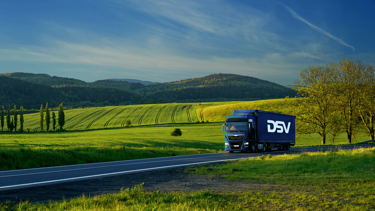 DSV-lastebil kjører langs grønne jorder.